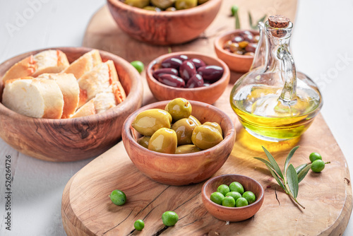 Healthy olives and extra virgin olive oil in wooden bowl.