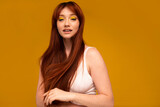 Positive ginger girl with yellow makeup, natural freckles, long hair and fringe. Happy red head woman posing in studio, looking at the camera.