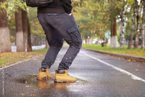 Autumn concept. Pedestrian feet on the road. Autumn leaves on the footpath. © alexkich