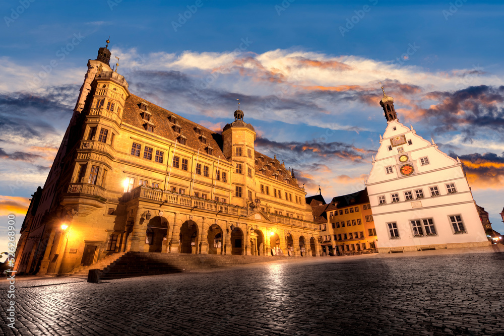 Das Rathaus, der Rathausturm, und die Ratsherrntrinkstube auf dem Marktplatz der historischen Altstadt von Rothenburg ob der Tauber in der Abenddämmerung, bei stimmungsvollem Himmel und künstlicher Be