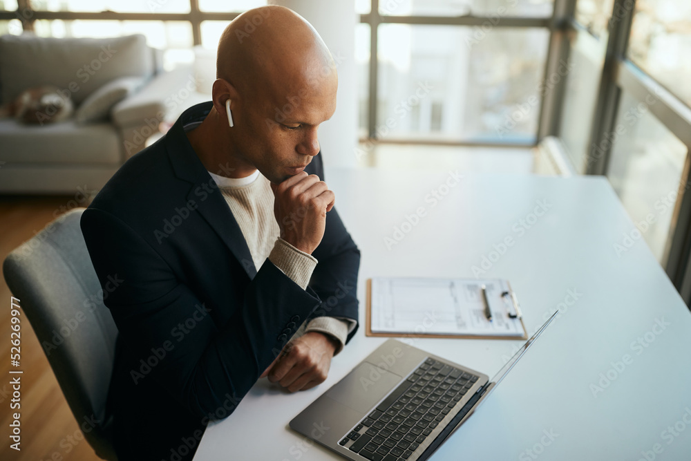 Pensive black businessman reads an e-mail on laptop in office.