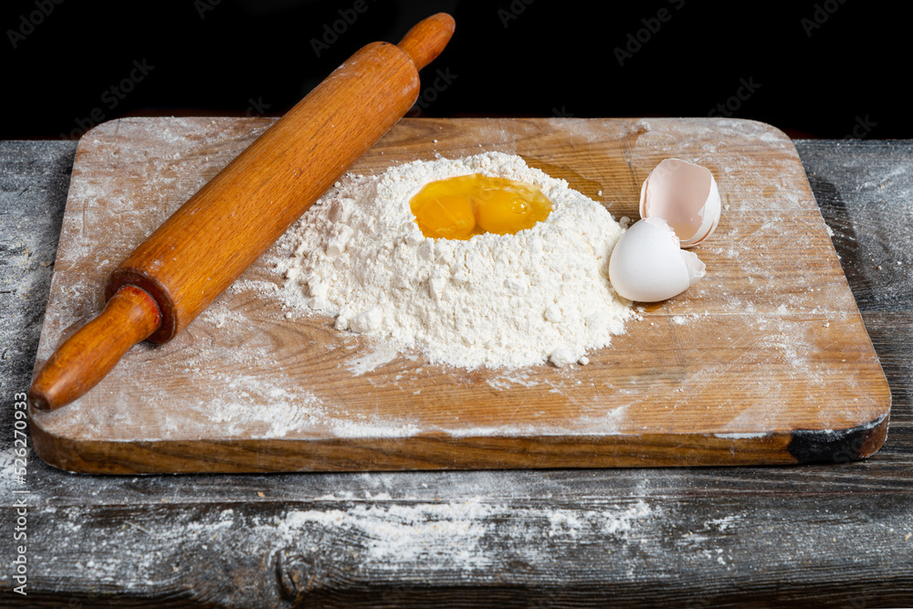 Making homemade dough for bread, pastry, and cookie. Wood rolling pin, flour, eggs. Rural food cooking. Top view Making homemade dough for bread, pastry, and cookie. Wood rolling pin, flour, eggs. Rural food cooking. Top view