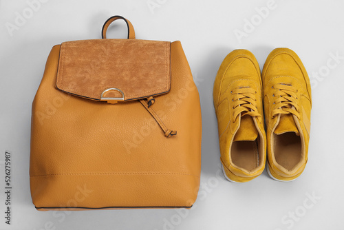 Backpack and sneakers on light grey background, flat lay