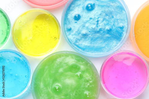 Photography Colorful slimes in plastic containers on white background, top view