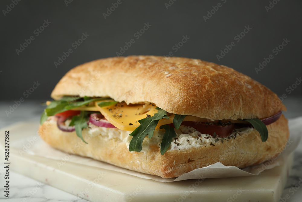 Delicious sandwich with fresh vegetables and cheese on white marble table Delicious sandwich with fresh vegetables and cheese on white marble table