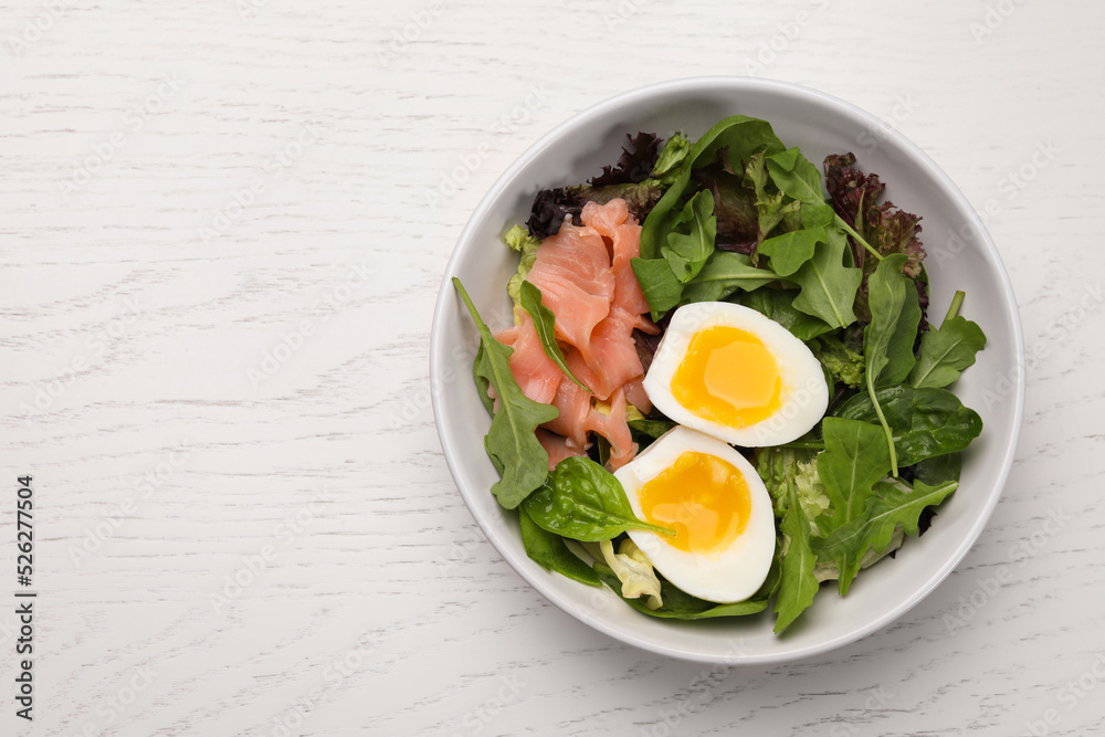 Delicious salad with boiled egg, salmon and arugula on white wooden table, top view