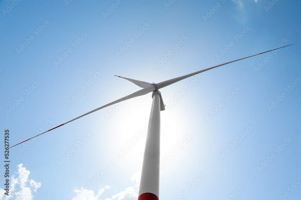 Modern wind turbine against blue sky, low angle view. Energy efficiency Modern wind turbine against blue sky, low angle view. Energy efficiency