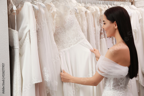 Fotografie Young woman choosing wedding dress in salon