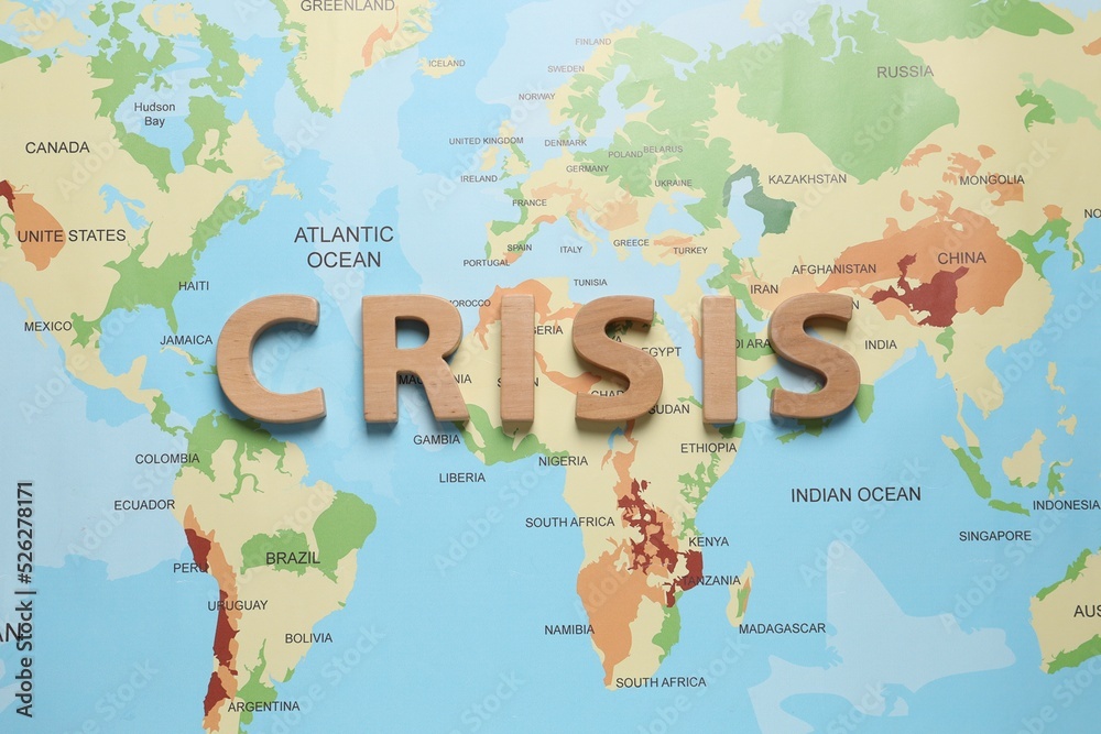 Word Crisis made of wooden letters on world map, flat lay