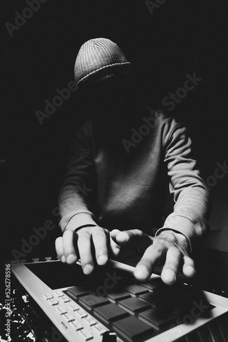 The hands of an artist creating music with drum machines. Beatmaker creates beats on a digital production controller with pushbutton pads. DJ plays the beats live on the pad controller.
