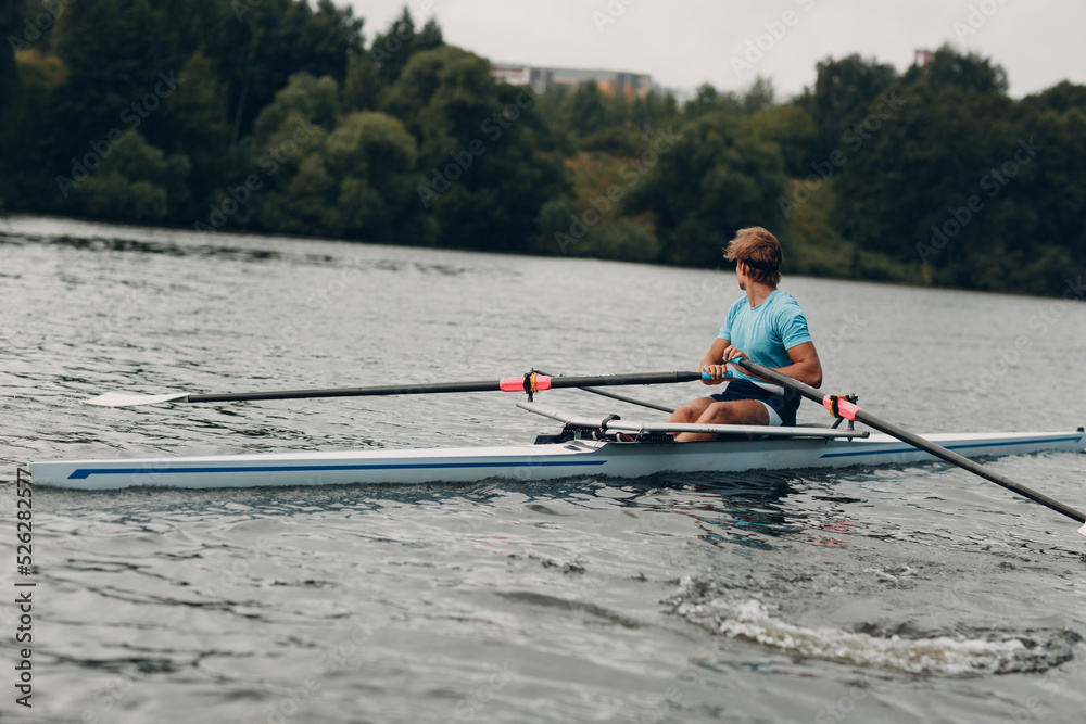 Sportsman single scull man rower rowing on boat. Sportsman single scull man rower rowing on boat.