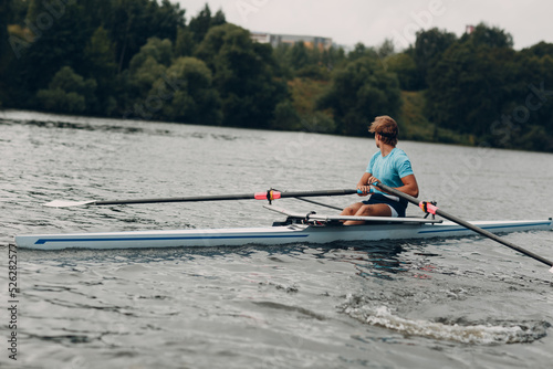 Sportsman single scull man rower rowing on boat.