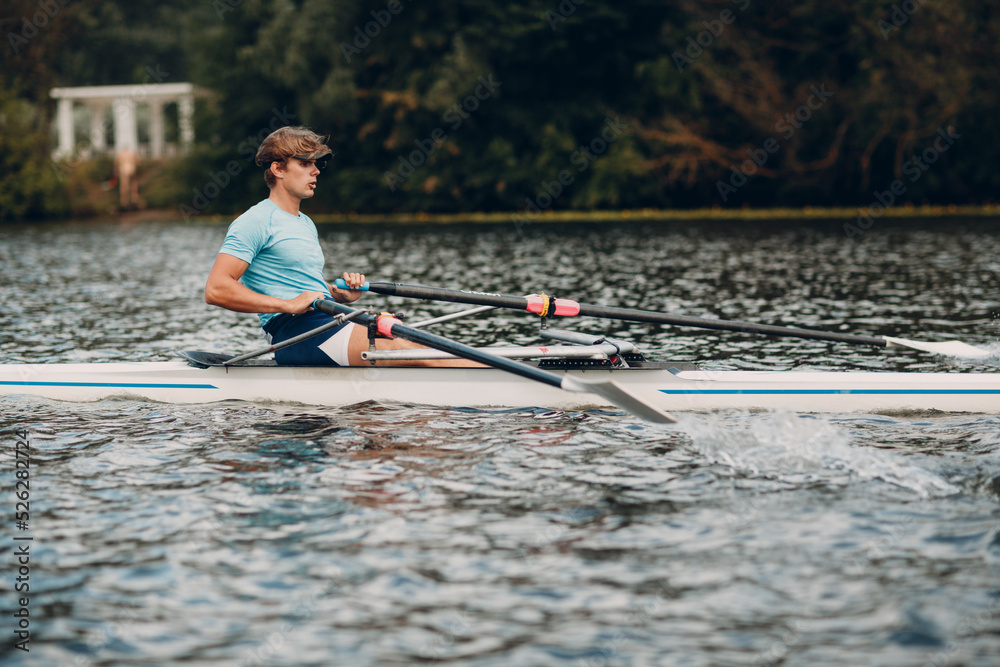 Obraz premium Sportsman single scull man rower rowing technique on boat. Paddle oar splash movement