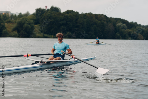 Sportsman single scull man rower rowing technique on boat. Paddle oar splash movement