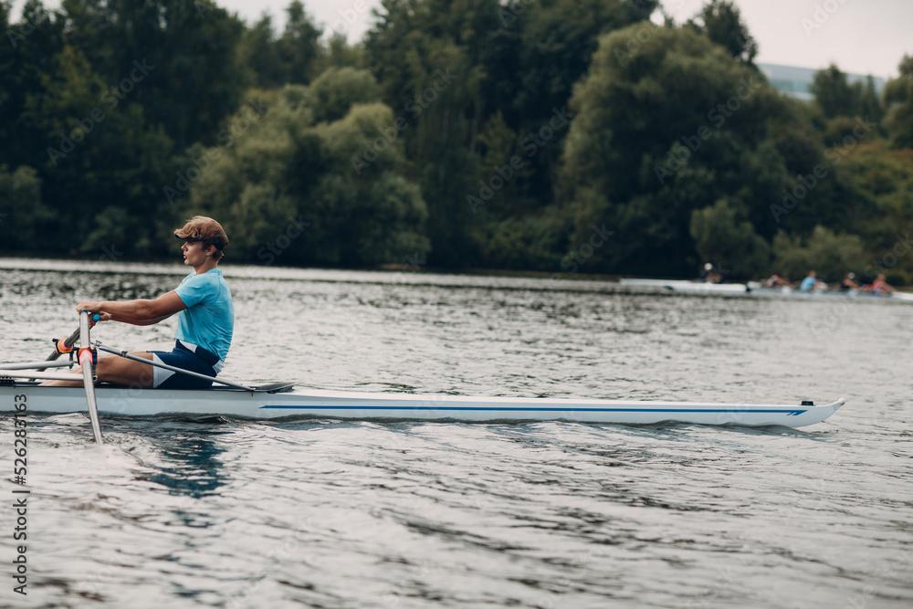 Sportsman single scull man rower rowing on boat.