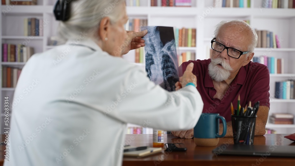 Female doctor shows X-Ray film to an elderly man old patient, provide professional medicare health insurance.