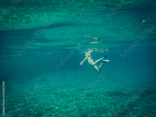 Underwater picture of woman swimming in the crystal clear, blue, Adriatic sea, Croatia during summer vacation