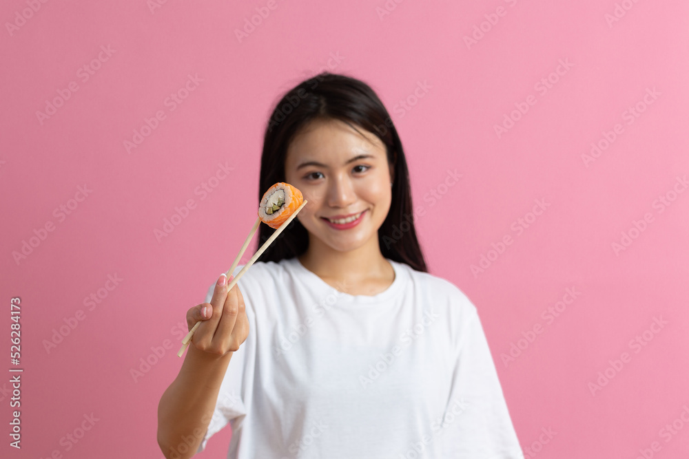 Asian beauty model girl eating Sushi roll, healthy japanese food. Beautiful woman holding chopsticks with Philadelfia roll. Asian beauty model girl eating Sushi roll, healthy japanese food. Beautiful woman holding chopsticks with Philadelfia roll.