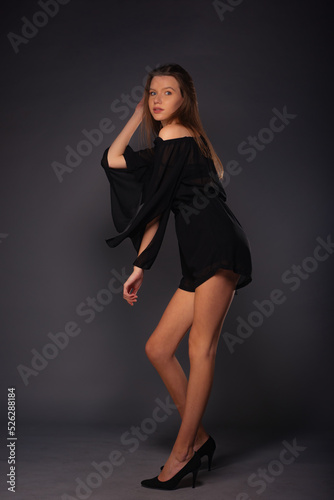 Full-length fashion portrait on a dark background of a beautiful female model wearing a little black dress