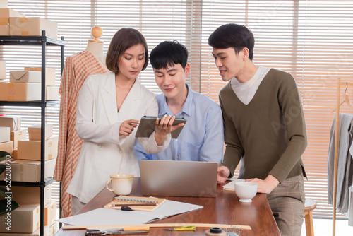 Young Asian business coworkers talking explain design dress and consult marketing plan sell online. businesswoman and man using laptop sitting at conference table in office. colleague work togerther. photo