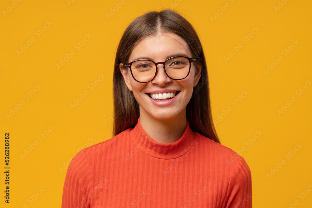 Headshot studio portrait of smiling woman, isolated on yellow background smiling at camera Headshot studio portrait of smiling woman, isolated on yellow background smiling at camera