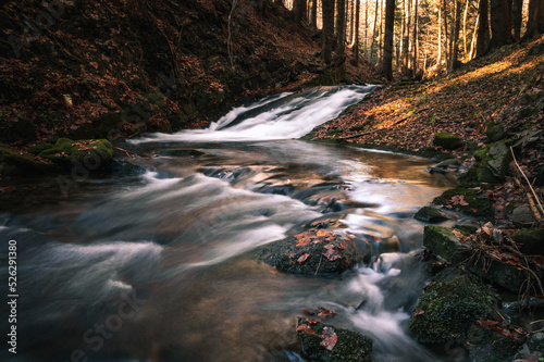 Water flowing in the Kytserov riverbed through the rocks creates small cascades around the banks, which are covered with colourful autumn leaves. Autumn is coming. Stare hamry, Czech republic, Europe photo