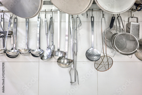 Kitchen Ladles, Cooking Skimmers and others Cookware hanging on the wall of a professional kitchen. photo