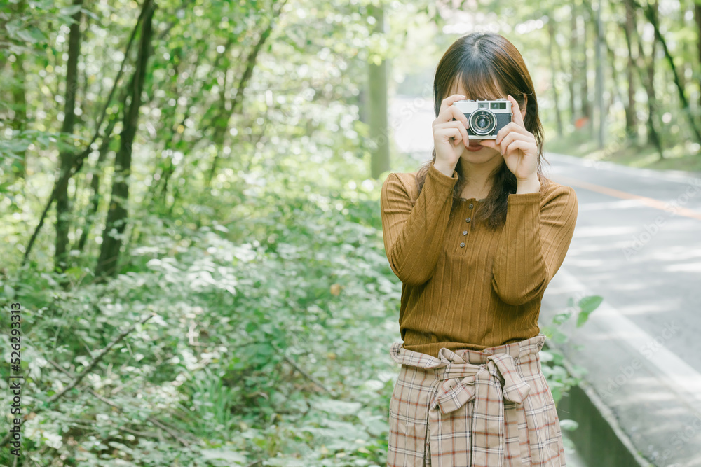 日本の女性がカメラを持って緑の中にいる　woman photographer