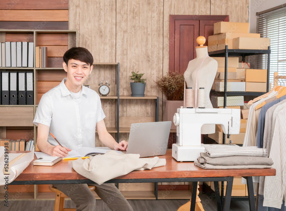 Young Business owner working fashion designer using laptop for find new collection dress, Asian man work from home design on notebook, smiling entrepreneur working on laptop at workplace. Young Business owner working fashion designer using laptop for find new collection dress, Asian man work from home design on notebook, smiling entrepreneur working on laptop at workplace.