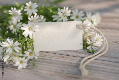 White flowers and blank white card for text. Mockup tag. Postcard