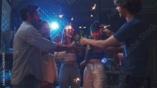 Diverse  young people clinking beer and waving sparkler on night party
