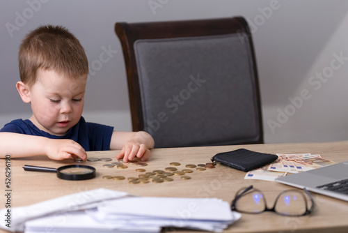 The boy counts and lays out money on a wooden table. 