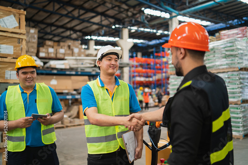 Industrial warehouse worker or engineer in safety suite handshake celebrate successful or deal commitment. Logistics , supply chain and warehouse business.Teamwork unity under view concept.