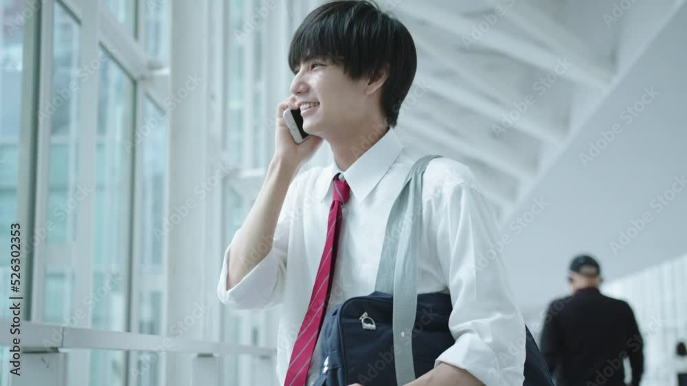 笑顔で電話をする男子高校生