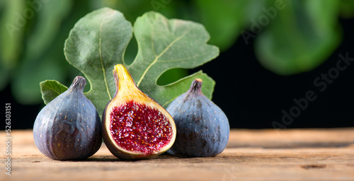 Fototapeta Naklejka Na Ścianę i Meble -  Ripe fig fruits with leaf close-up. Beautiful sweet fresh organic figs on a wooden table. Label design. Healthy vegan food