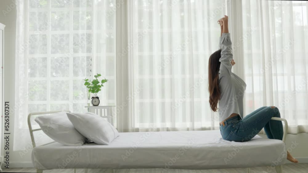 Young caucasian woman stretch oneself on bed in a white bedroom. Young caucasian woman stretch oneself on bed in a white bedroom.