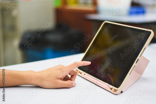 Close-up of Asian woman's hand pressing a tablet