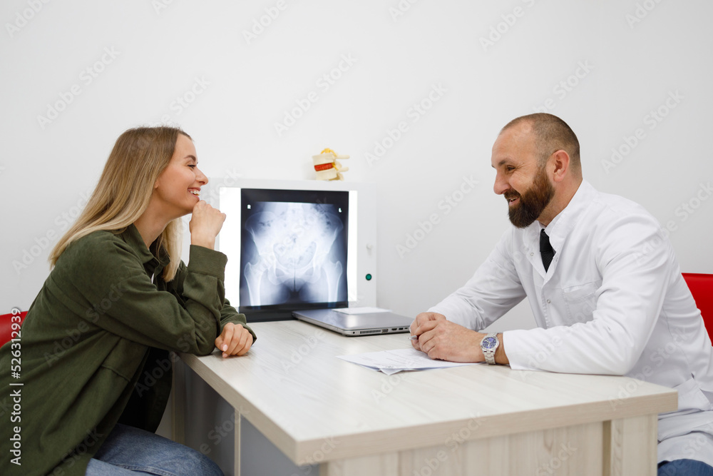 Young female patient of a private clinic talking to a orthopedic or traumatologist doctor