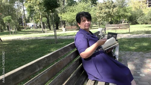 A woman sits on a park bench and reads a book.
   Summer woman sit on a bench in a blue dress and reads a book.