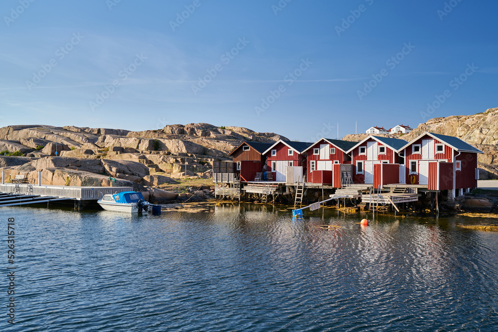 typical fishermen's houses with many colours reflected in the water of the fjord and a cliff of granite rocks behind
