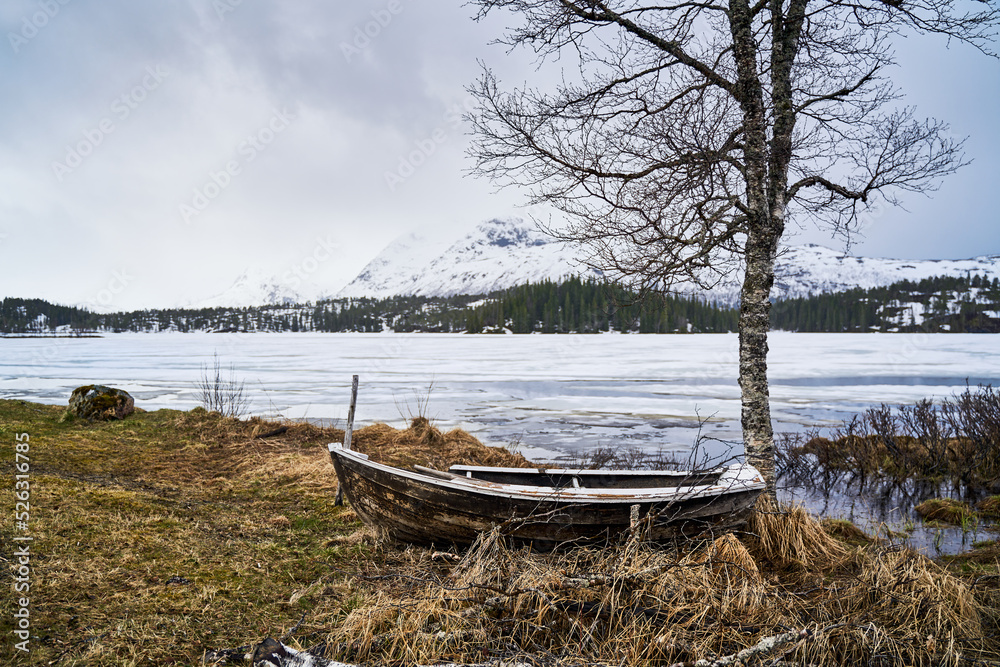 ship stranded in the Norwegian highlands with frozen lake in the background and snow-capped mountains