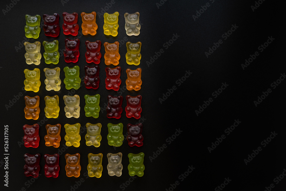 top view of multi-colored gummy bears arranged in rows by color as a gradient