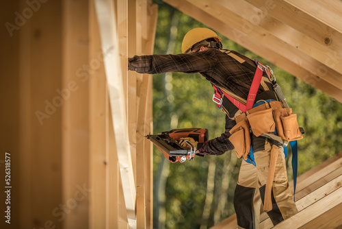 Contractor Working on Wooden Skeleton of the House with Nail Gun
