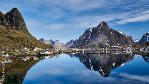 Midnight light in the village of Reine in Lofoten, Norway overlooking the bay reflecting the mountains and houses on the water.