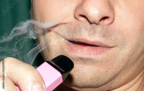 A man smokes an electronic cigarette.The electronic cigarette is disposable.Vape smoking.Vape with strawberries and ice cream.