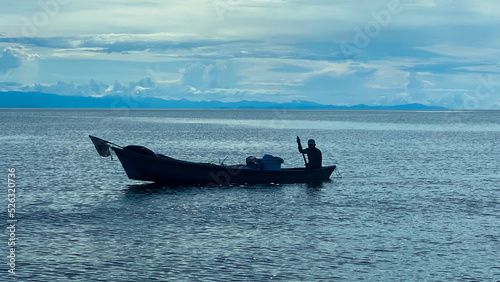 fisherman silhouette rowing a boat in the middle of the sea