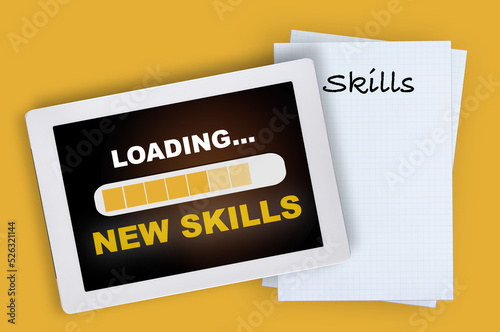 New skills loading on computer digital tablet and skills written on grid paper on yellow background. Digital technology and traditional concept and education idea