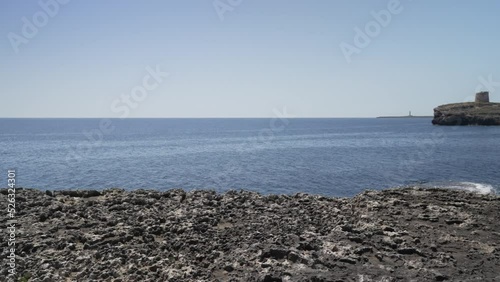 Rocky coastline and Torre de Alcaufar landmark at Alcaufar, Menorca, Balearic Islands photo