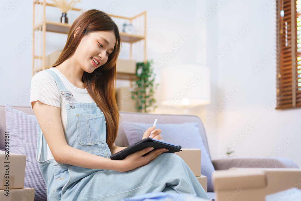Online seller concept, Female entrepreneur checks online orders on tablet to prepare parcel boxes