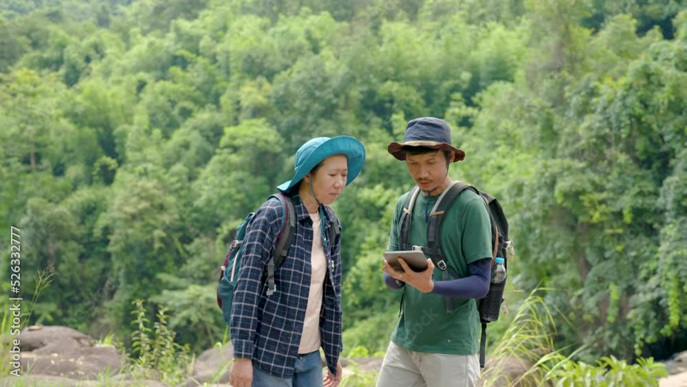 4K, Two Asian lovers, walk and stand on a large rock, And the two of them looked at the direction of their walk and used both hands to point to the path, and looked for the path, eagerly. 4K, Two Asian lovers, walk and stand on a large rock, And the two of them looked at the direction of their walk and used both hands to point to the path, and looked for the path, eagerly.